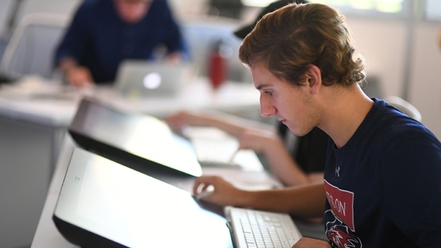 Male student in class working on computer